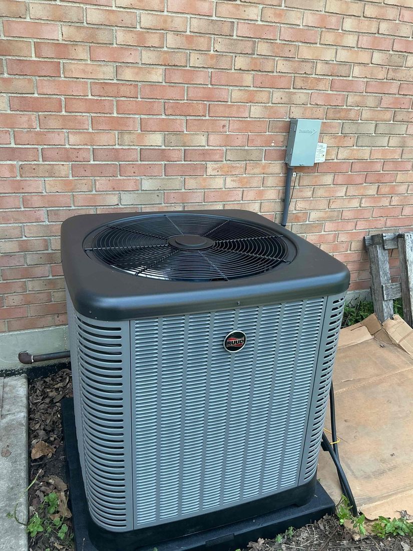 A Ruud air conditioner installed beside a brick home