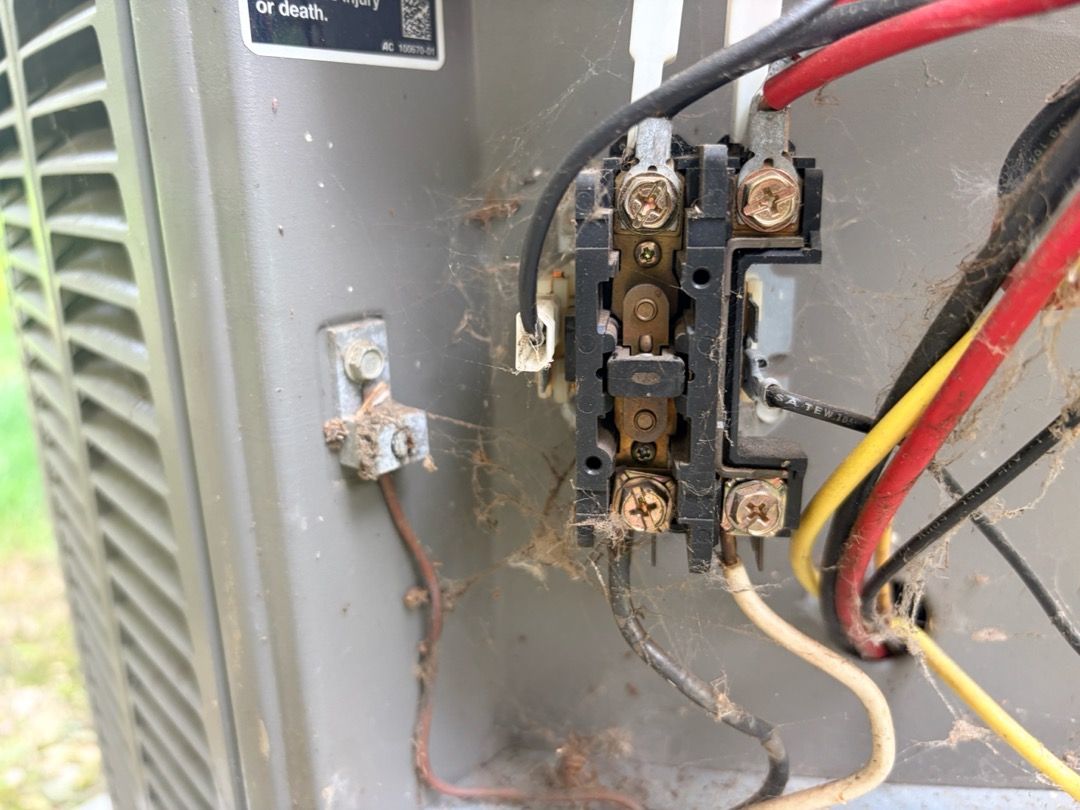 A worn, cobwebbed contactor found inside an air conditioner during a service call
