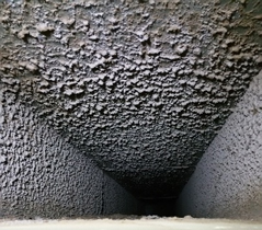 The inside of an air duct heavily coated with dust